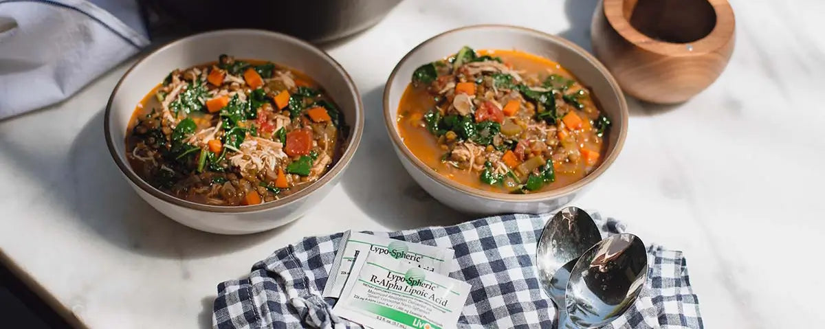 bowls of chicken and lentil soup on a counter with dishcloth and packets of lypo-spheric r-alpha lipoic acid